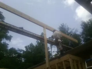 Carpenter setting a ridge beam over a new addition frame — Ice Dam Removal by Roofing Brothers in Poolesville