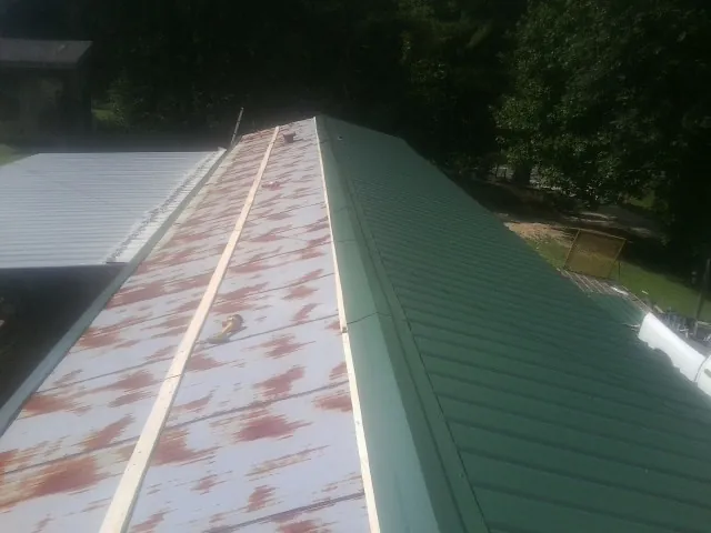 Old rusted panels beside newly installed green metal roofing — Wind Damage Roof Repair by Roofing Brothers in Poolesville