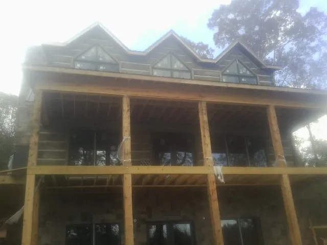 Dormers and porch framing on a large log home under construction — Roof Coating work by our crew in Poolesville